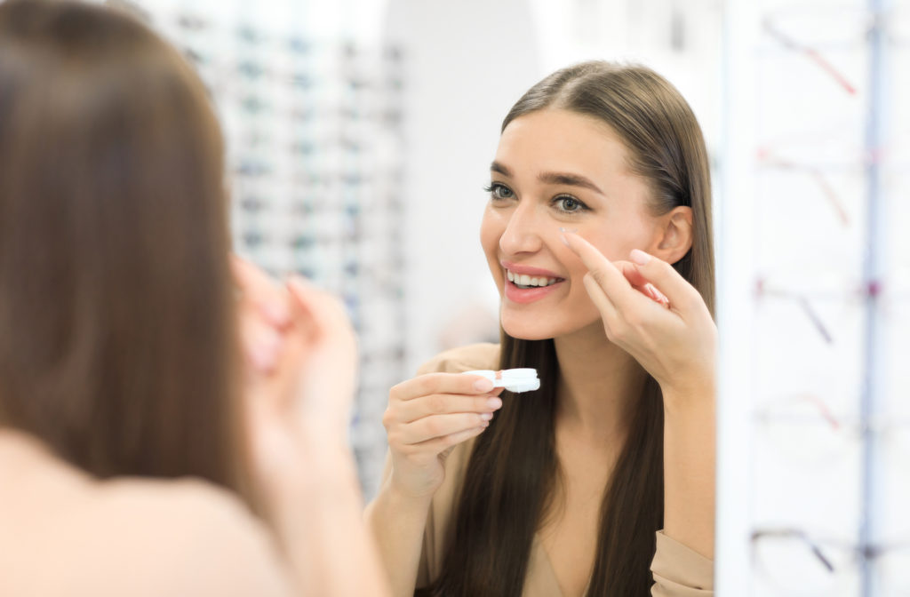 Young girl putting on contact lenses at optometrist office