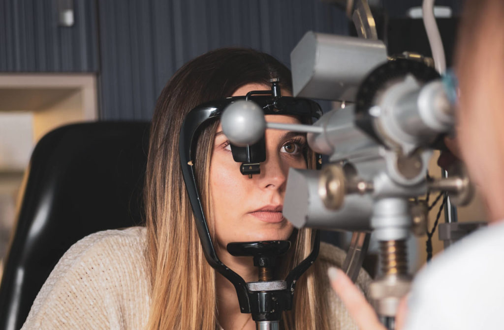 A close-up of a woman looking through a keratometer while the optician is measuring the size, shape, and curvature of the eye for scleral contact lenses.