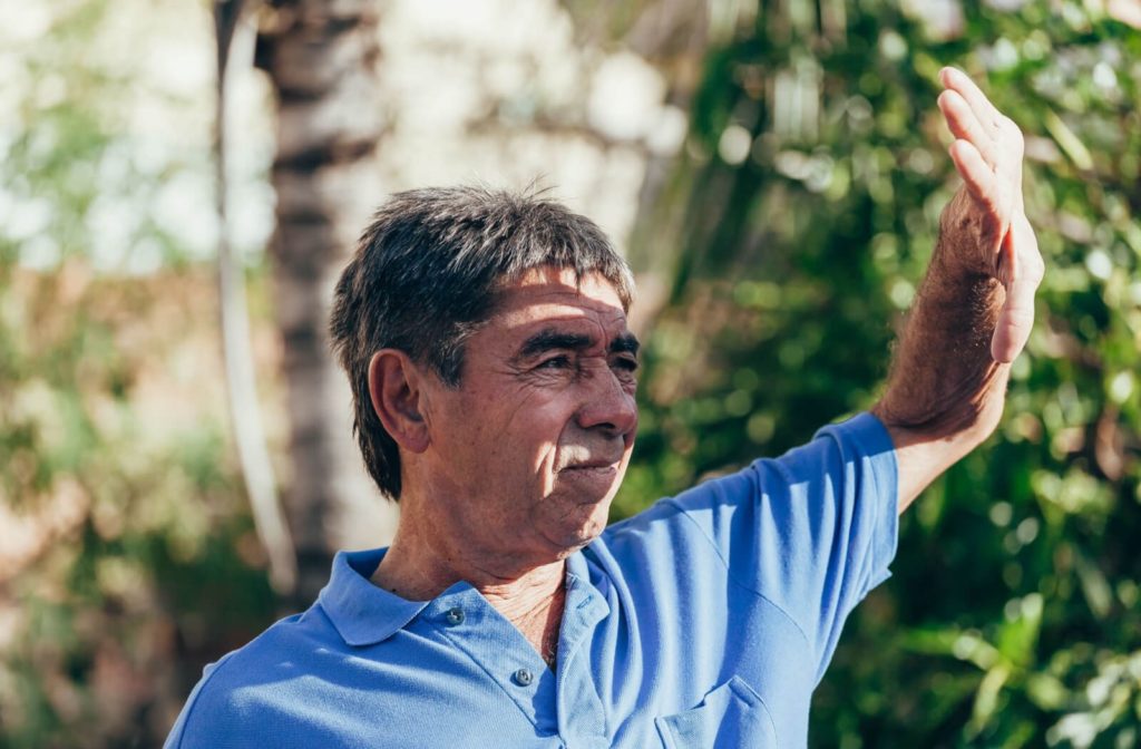 A senior man raising his hands to block out the sun to see more clearly.