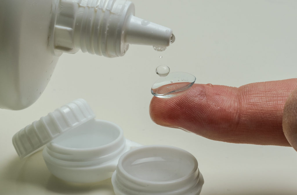 A close-up of a scleral lens being cleaned using a cleaning solution.
