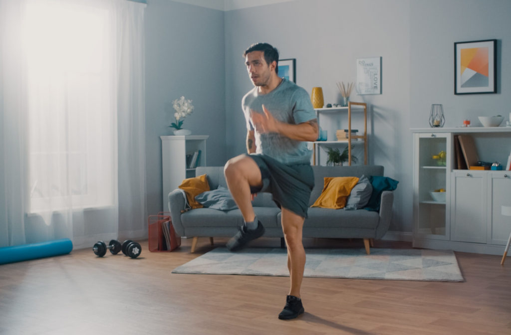 A young man jogging in place in his living room as a part of his exercise routine.