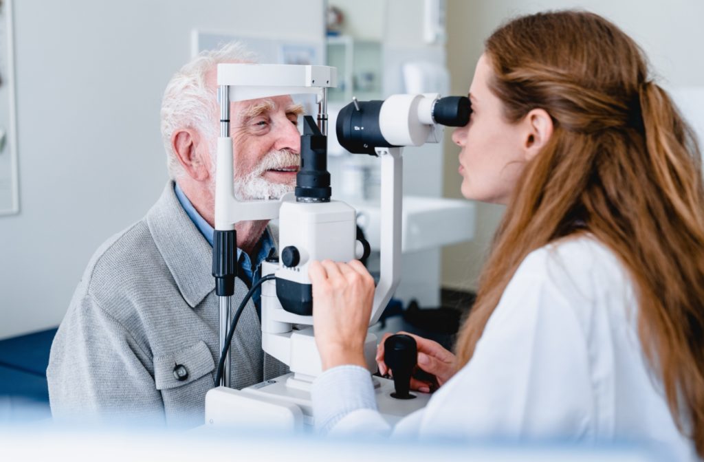 A senior man smiling during an eye exam to find out if he needs cataract surgery to correct his vision.