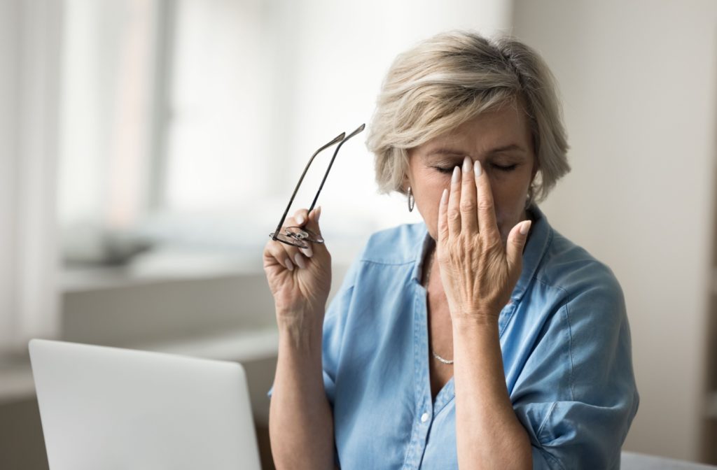 A person sitting at their desk rubbing their itchy watery eyes