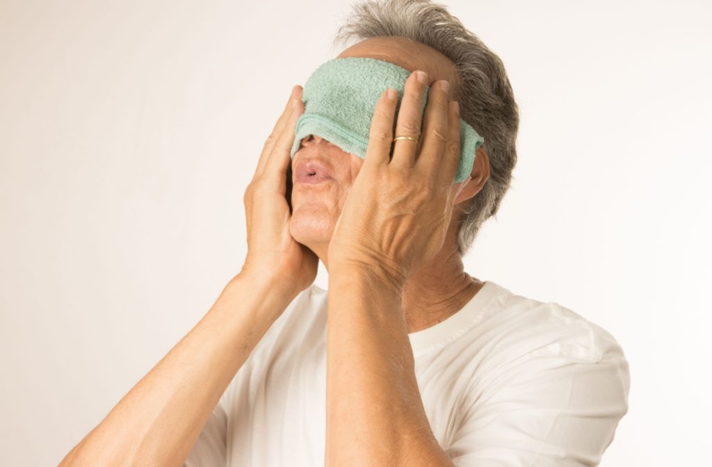 A person using a warm compress for relief from their itchy watery eyes.