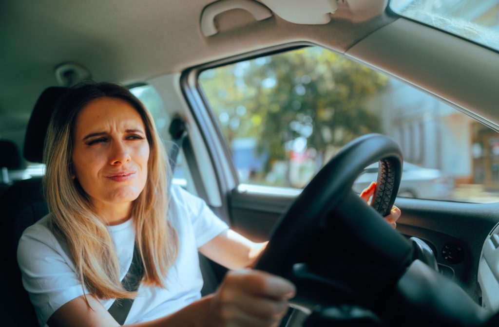 A patient attempting to drive home after having their eyes dilated, squinting from the bright daylight