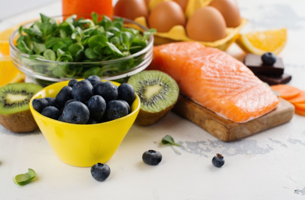 A variety of healthy, whole foods that are eye-friendly are grouped together on a white countertop.