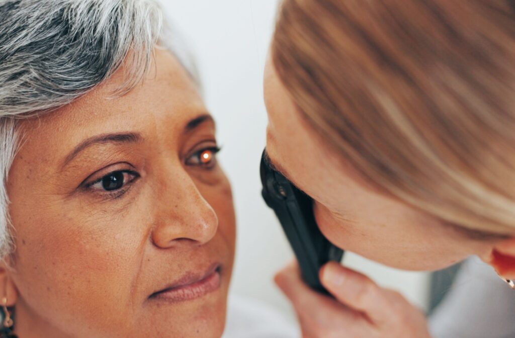 An eye doctor using a light to examine a patient's eyes who has been experiencing flashing in their vision
