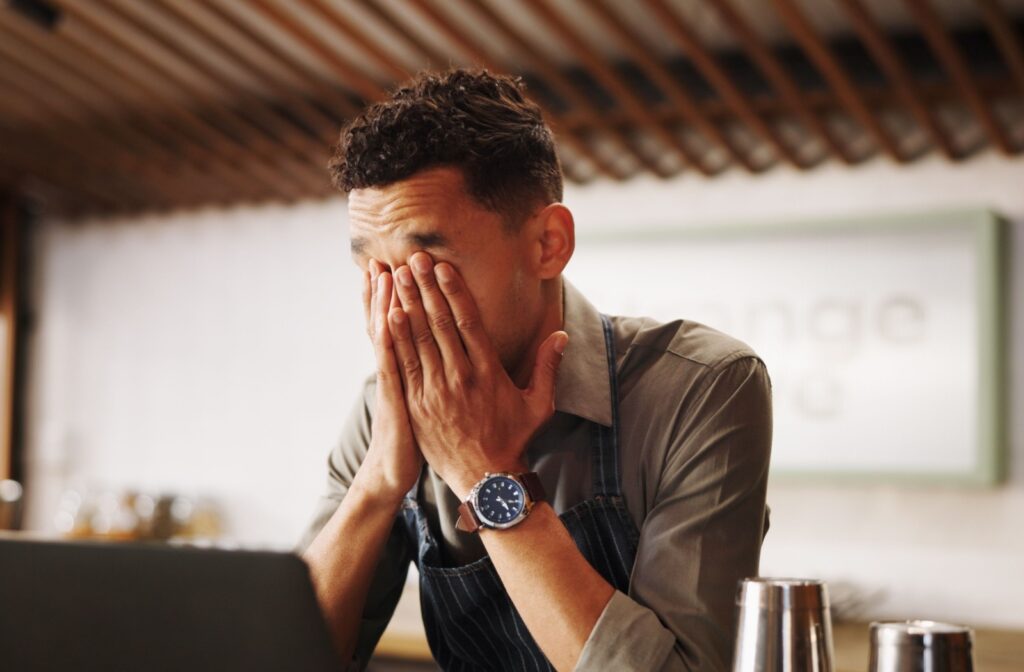 A person holding their hands up again their eyes because they are experiencing eye strain and headaches due to vision problems.