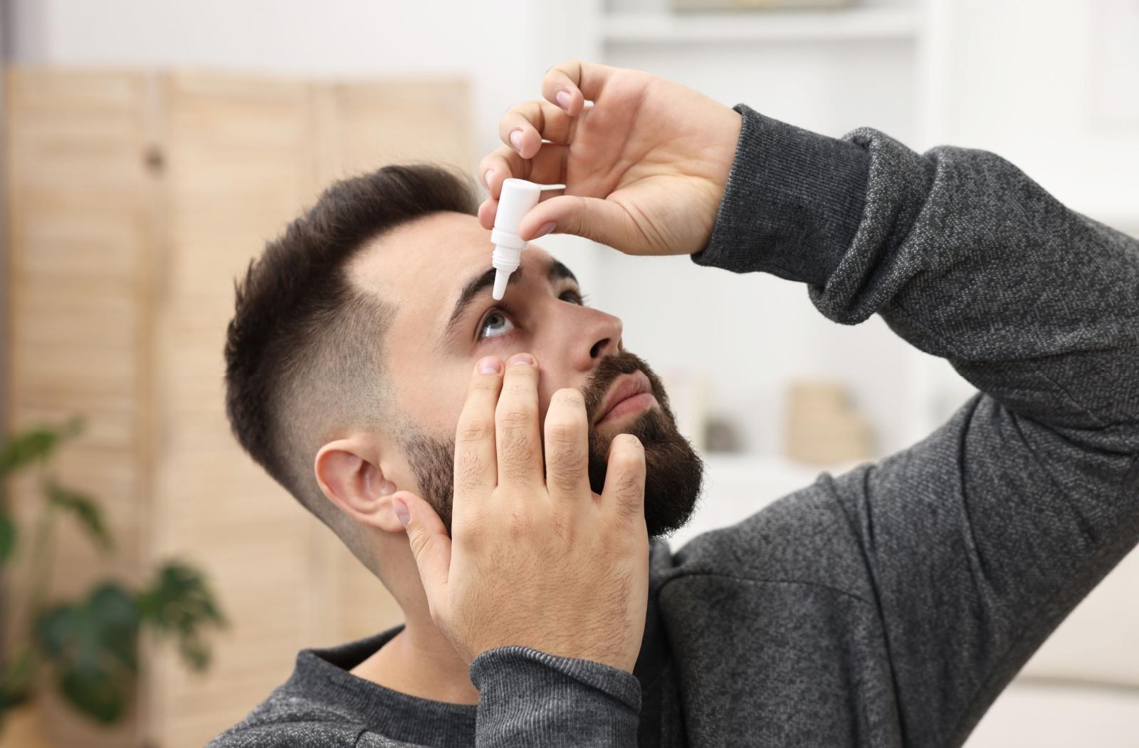 A person flushing their eye with sterile saline drops.